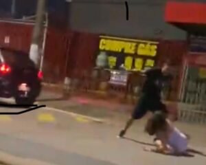 Um circuito de segurança flagrou o momento das agressões e mostra o suspeito derrubando a vítima no chão, desferindo socos, chutes e ainda arrastando a jovem pela via pública.
